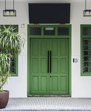 A freshly painted green front door with a plant on the side.